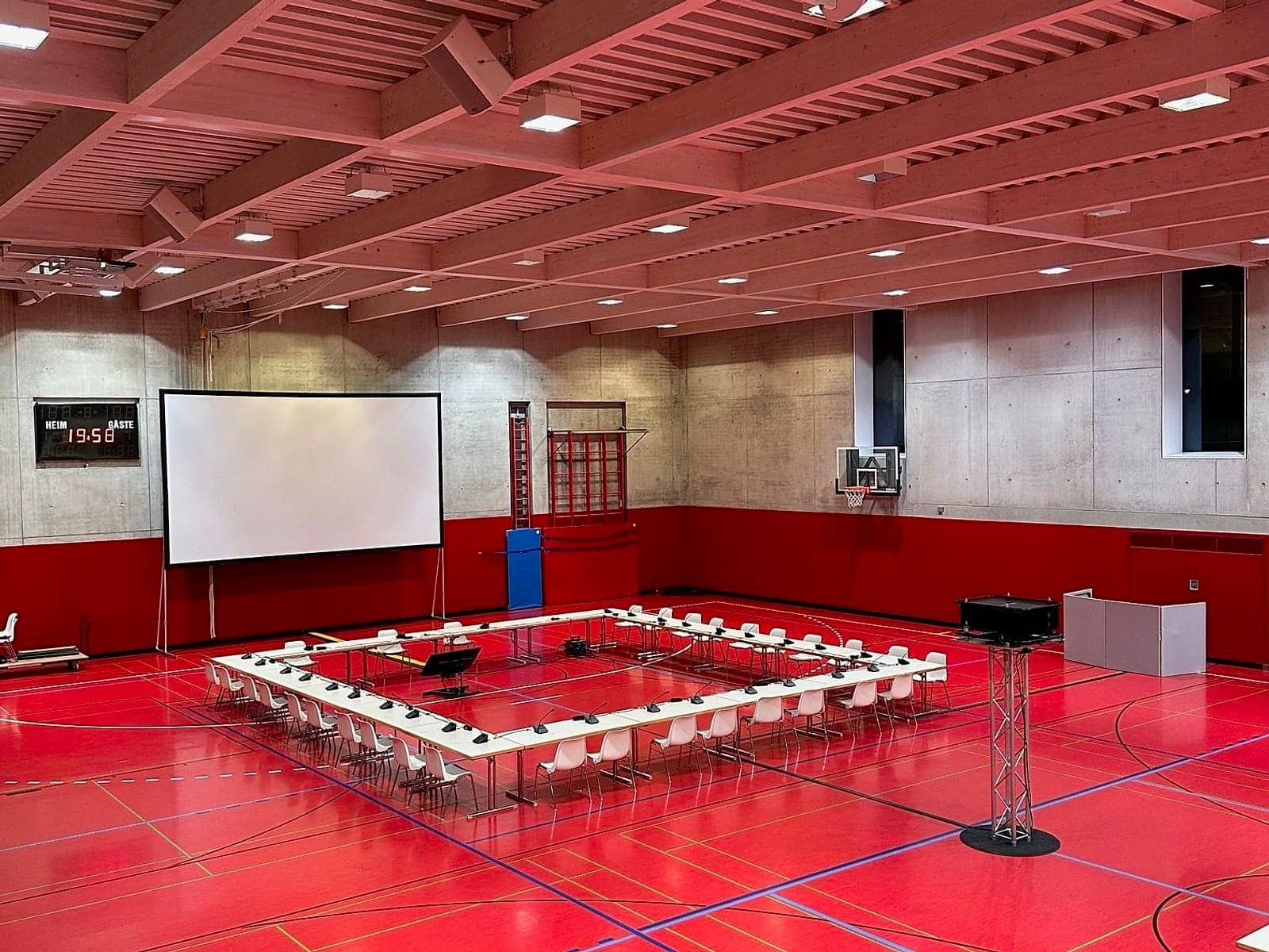 Preisgerichtssitzung mit Leinwand in roter Sporthalle